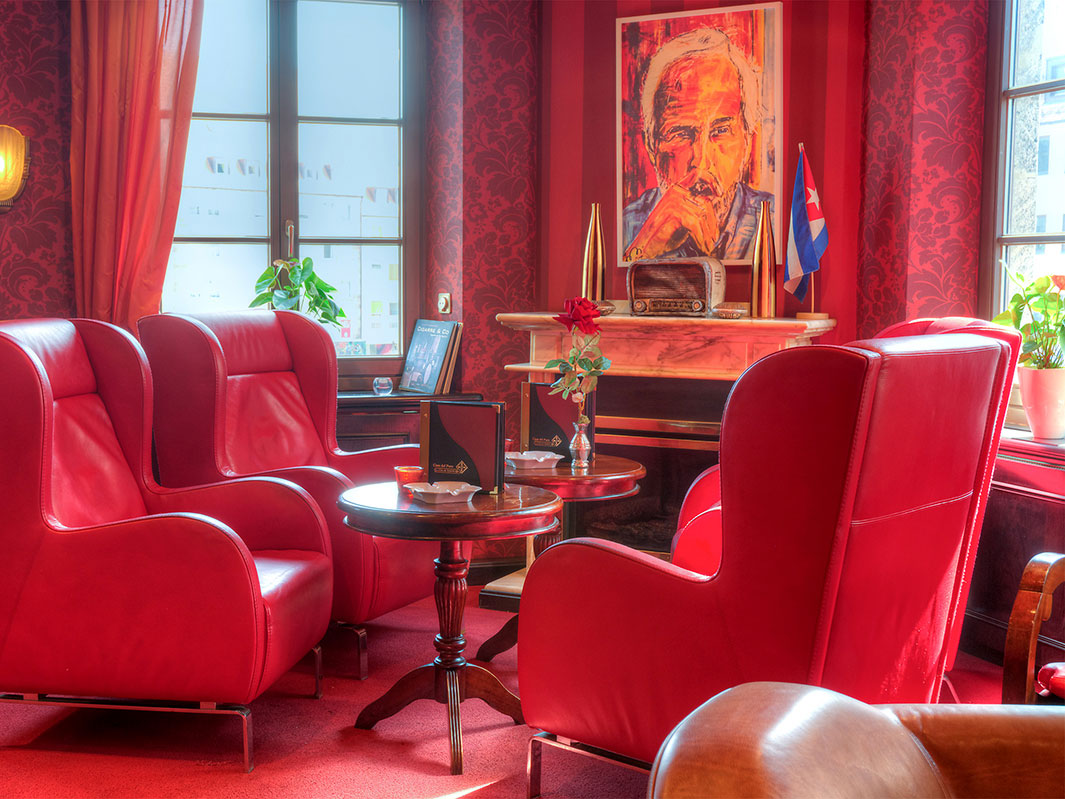 Lounge-Bereich mit roten Ledersesseln, einem Gemälde-Porträt und einer kubanischen Flagge